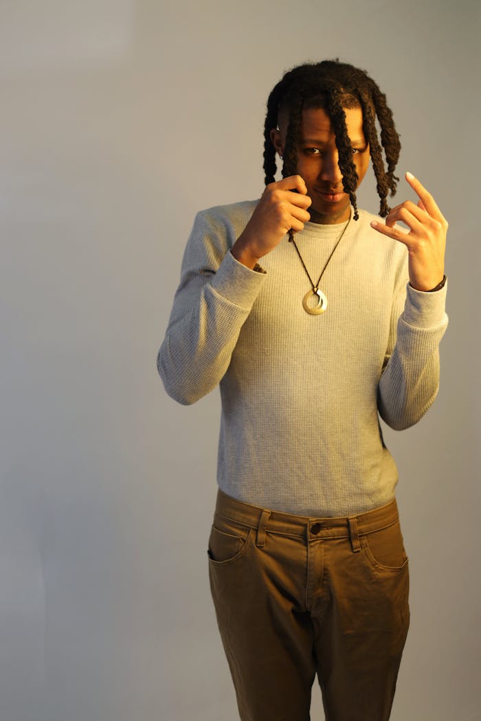 Portrait of a stylish man gesturing in a studio with a spotlight and neutral background.