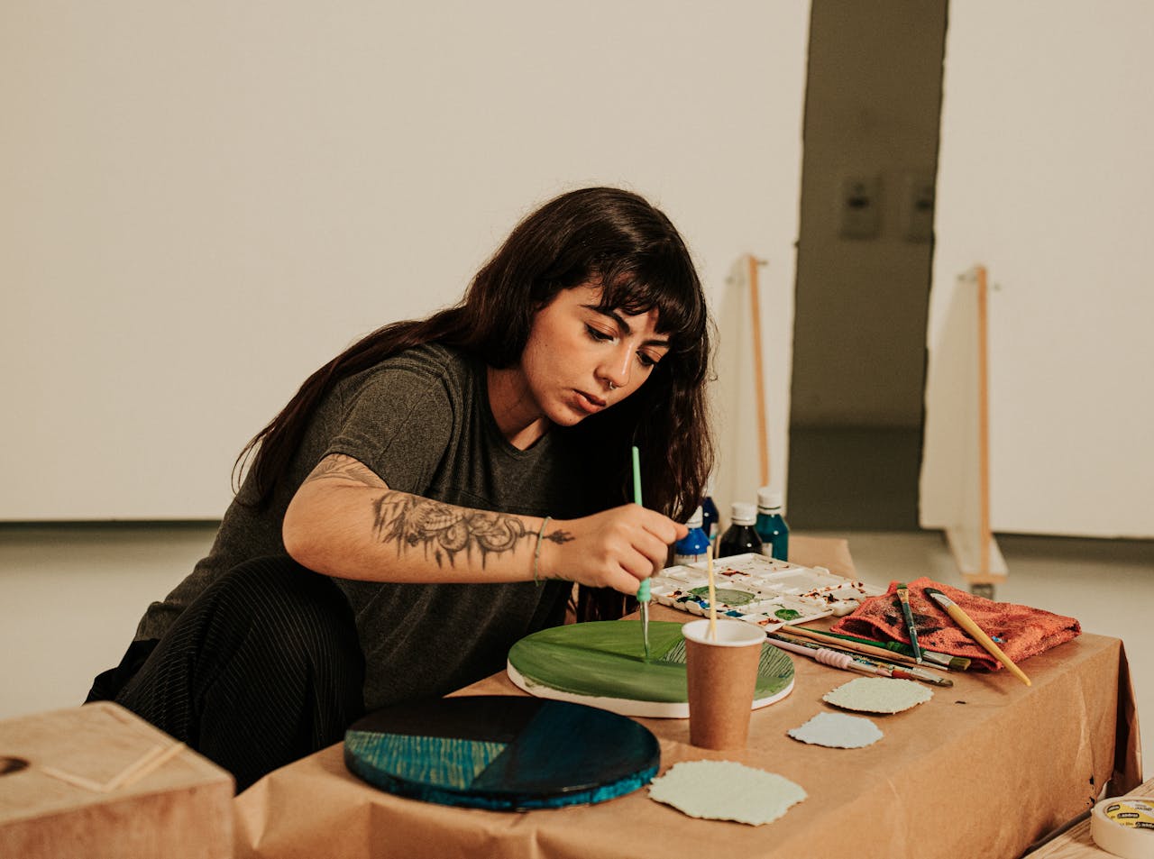 A focused woman creating art with brushes and colors in an indoor studio.
