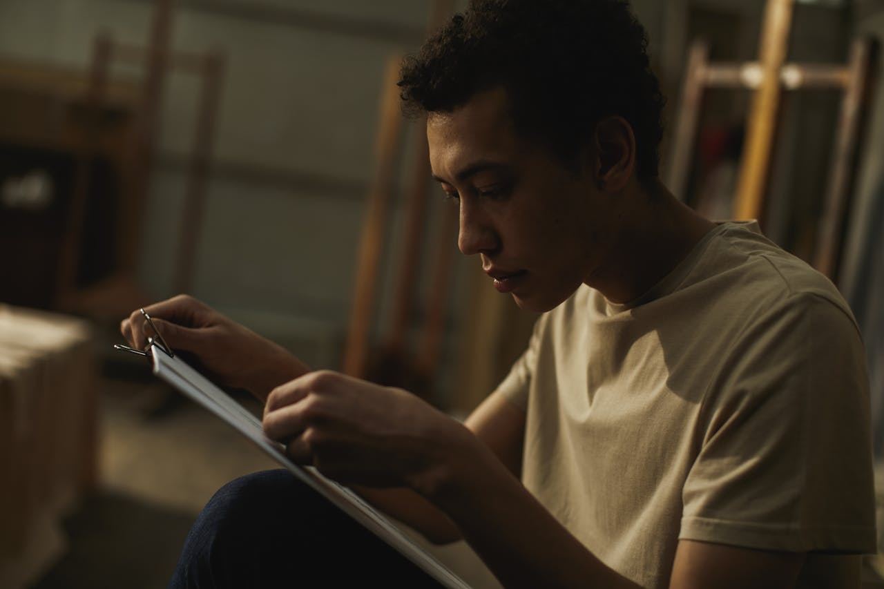 Mastering the First Impression: Your intriguing post title goes here A young man deeply focused on creating art in an indoor workspace.